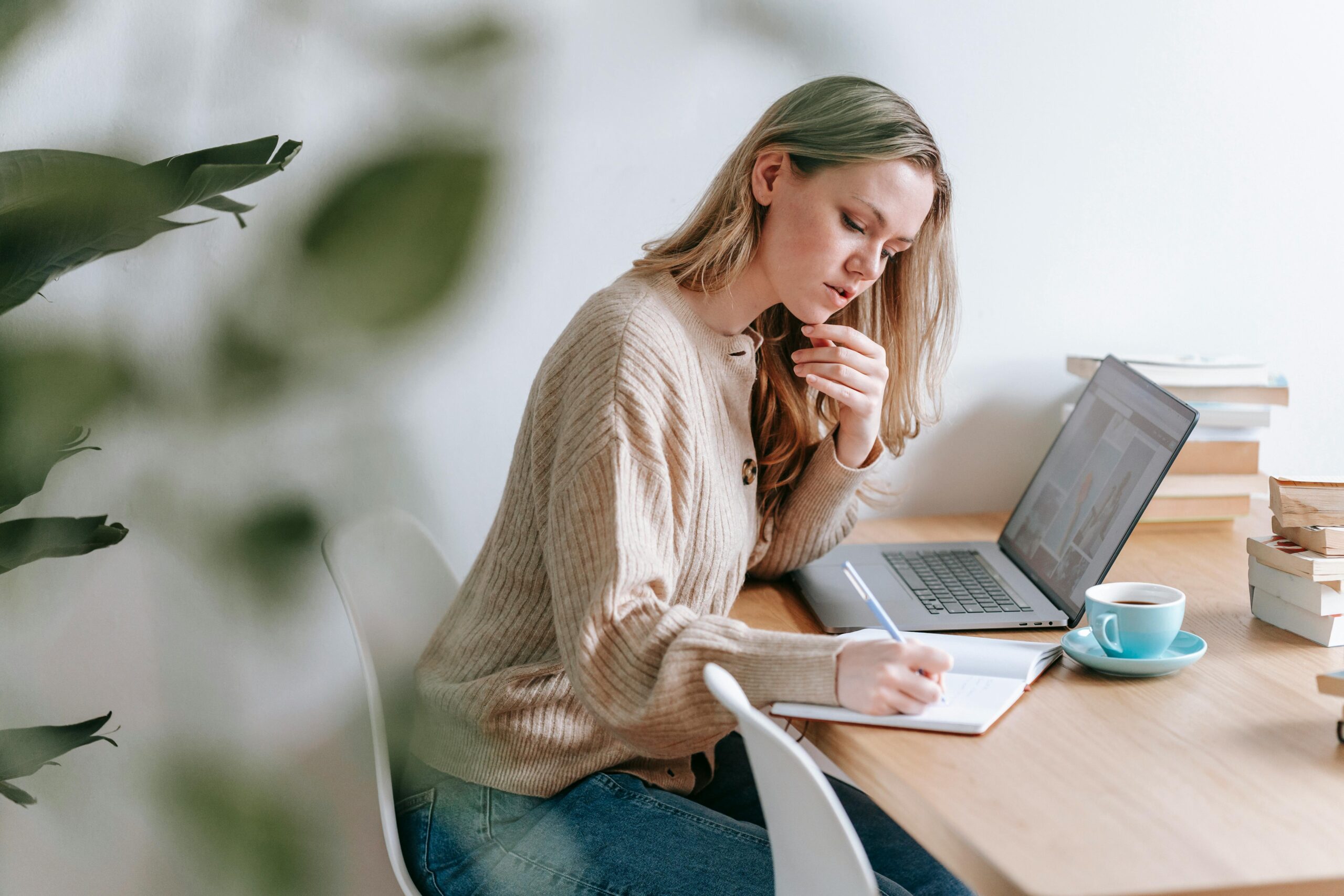 A woman taking notes at a table, reflecting on career planning.